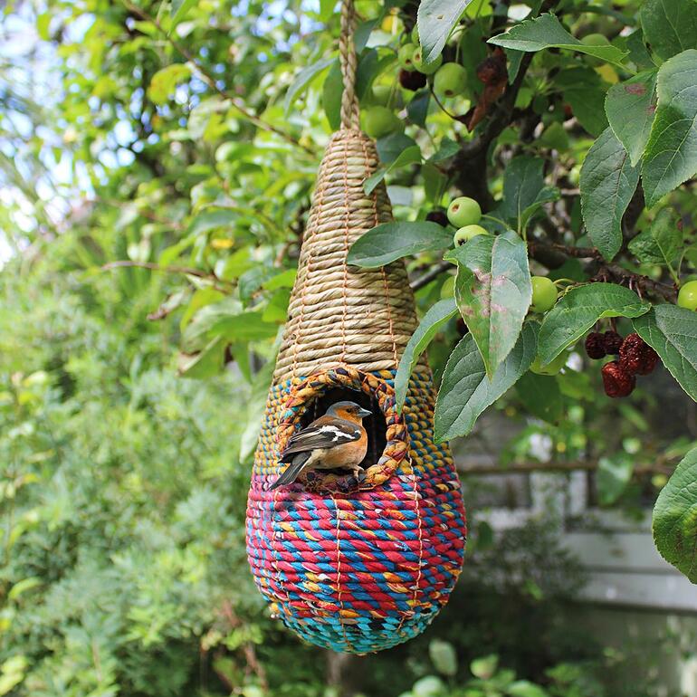Artisan vogelhuisje van gevlochten materiaal, hangend aan een boom