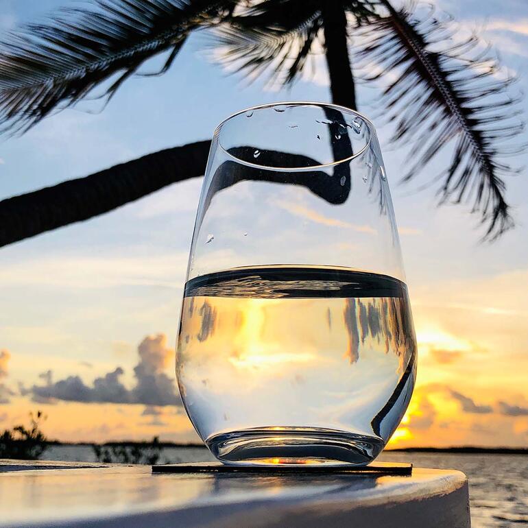 Glas met helder water, zonsondergang op de achtergrond