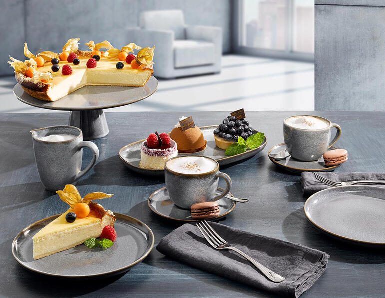 Servies met verschillende borden, mokken en taart op een tafel.