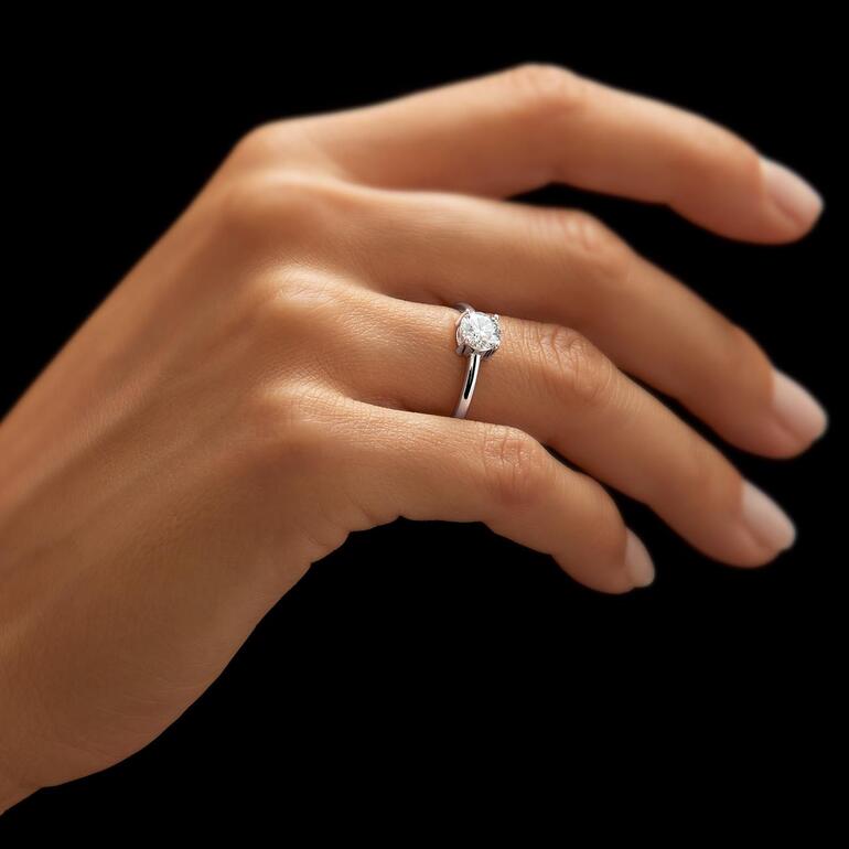 Close-up van een rhodium-geplateerde Moissanite-ring aan de vinger van een persoon.