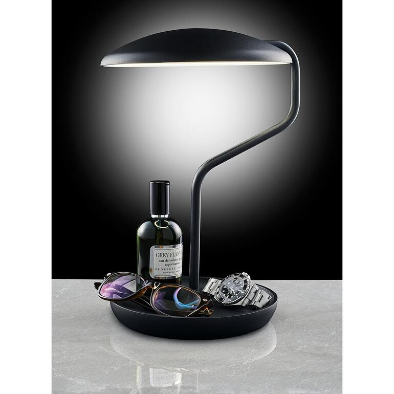 Als u het spiegeloppervlak naar beneden draait, verandert u het multitalent in een veelzijdige tafellamp met een praktisch opbergbakje. Moderne LED-lamp met accessoires op een tafel.