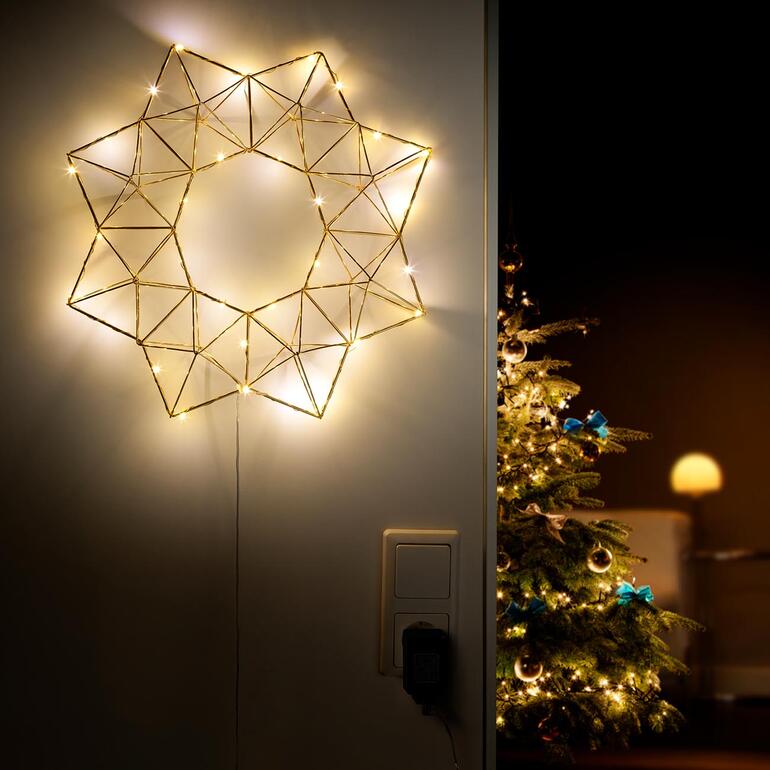 Piramide lichtster aan de muur, verlicht met warm licht.