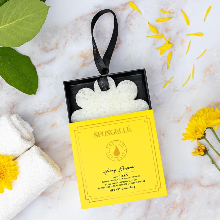 Spongellé schoonheidsspons in een gele verpakking met natuurlijke decoratie.