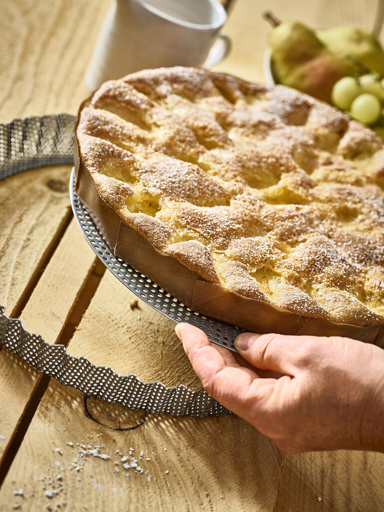 Perforeerde roestvrijstalen bakvorm met vers gebakken taart.
