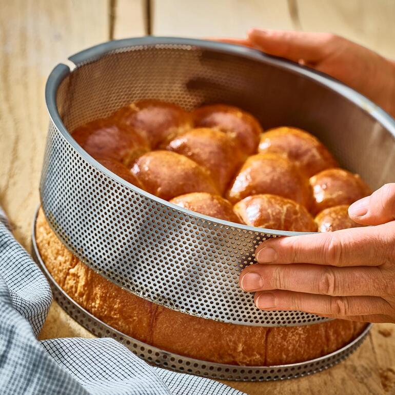 De ring van de taartvorm tilt u heel eenvoudig van de losse geperforeerde bodem. Perforeerde roestvrijstalen bakvorm met vers gebakken brood.