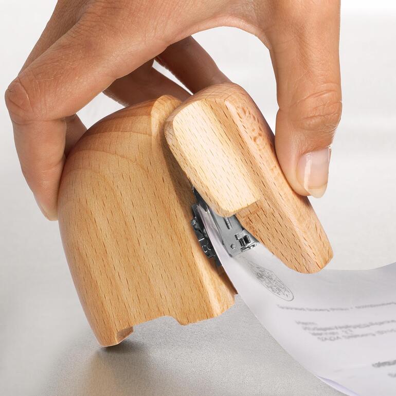 Nietmachine olifant Hand houdt papieren vast terwijl ze een houten olifanten-nietmachine gebruikt.