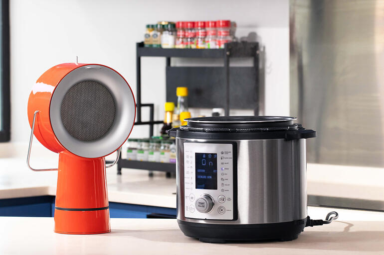 AirHood™ Rode AirHood™ naast een elektrische kookmachine op een aanrecht.