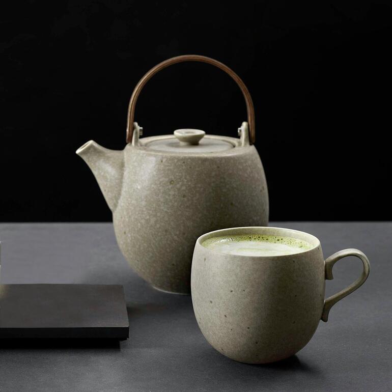 Theepot of Kopje, set van 6 NESUTO Theepot en beker in grijs keramiek op een donkere tafel met groene thee in de beker
