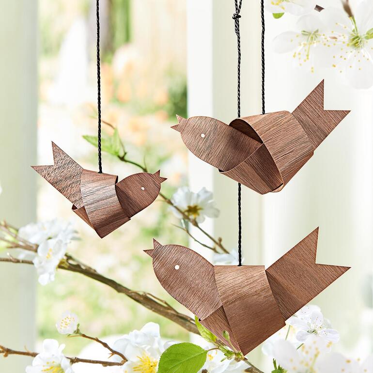 Drie houten knoopvogels die aan een tak hangen