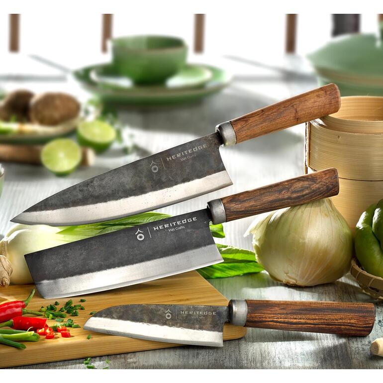 Drie carbonstalen keukenmessen op een snijplank