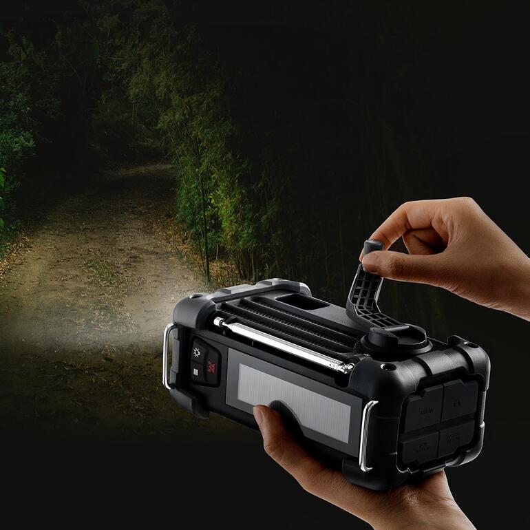 Hand aan een digitaal survivalradio met licht in een donkere omgeving.