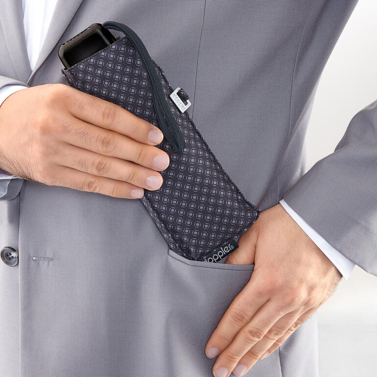 Handen steken een carbonstalen tasparaplu in een zak van een pak.