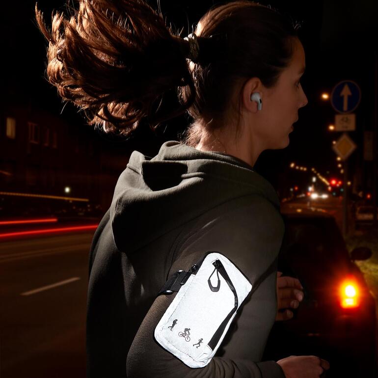 Reflector-armtas tijdens het hardlopen in de schemering.