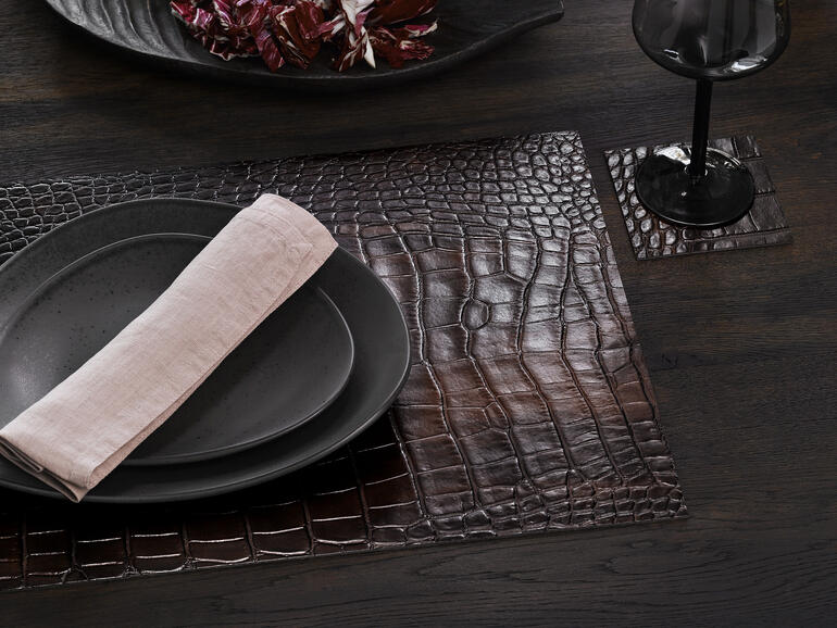 Gedeckte tafel met krokodillen set en glazen onderzetters, geserveerd met servies.