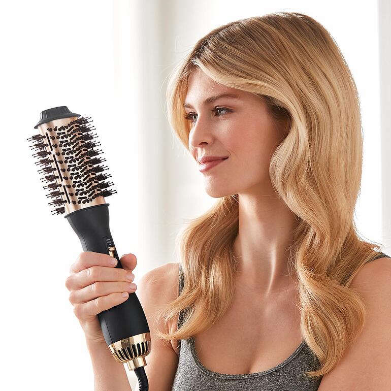 Vrouw houdt een 4-in-1 warmeluchtborstel vast en glimlacht.
