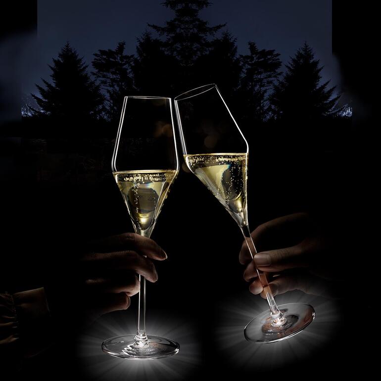 Twee verlichte champagneglazen op een buitentafel