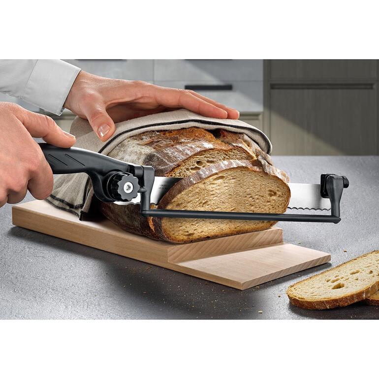 Persoon snijdt brood met een speciaal mes op een stapel snijplank.