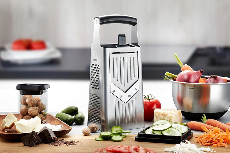 Torenrasp met V-schaaf op een keukentafel, omringd door verse groenten en ingrediënten.