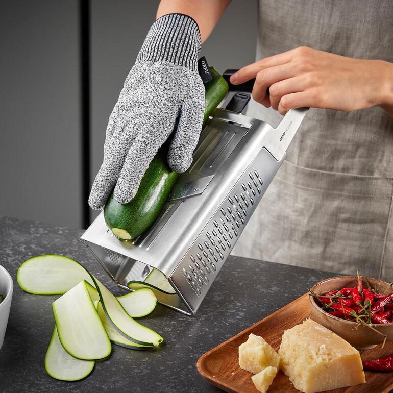 Hand aan een torenrasp die een courgette raspt.