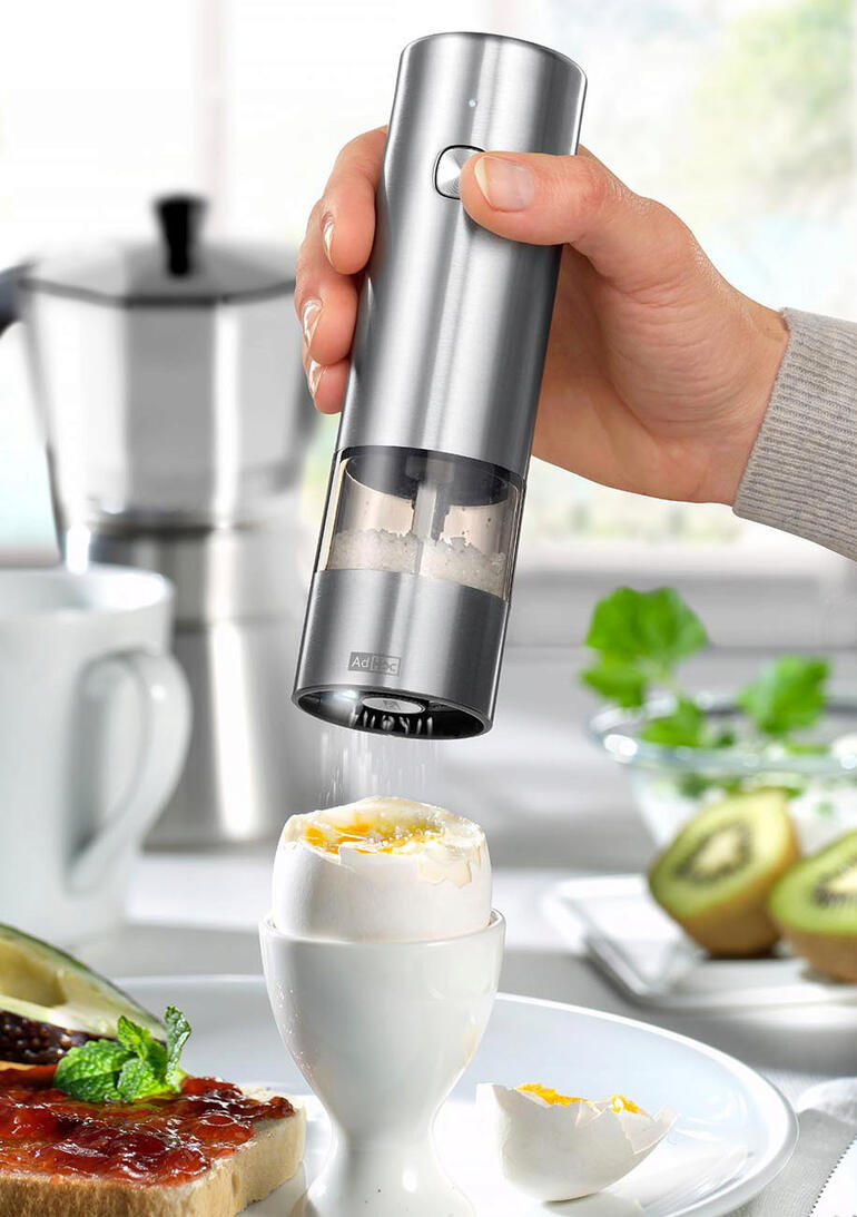 Hand houdt een accu-pepermolen boven een ei met een punt.