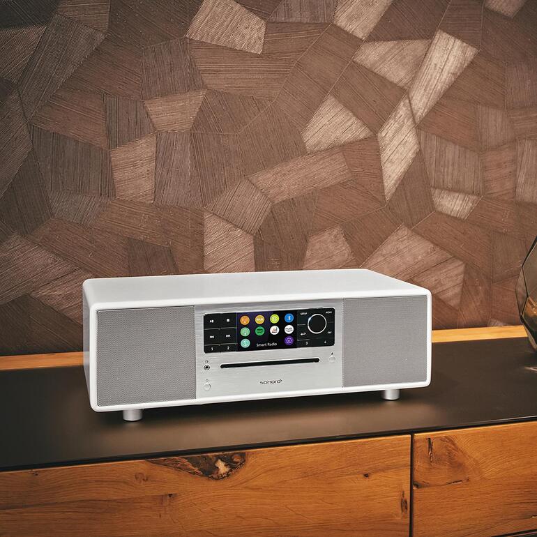 Sonoro PRESTIGE in het wit op een donkere tafel voor houten panel.