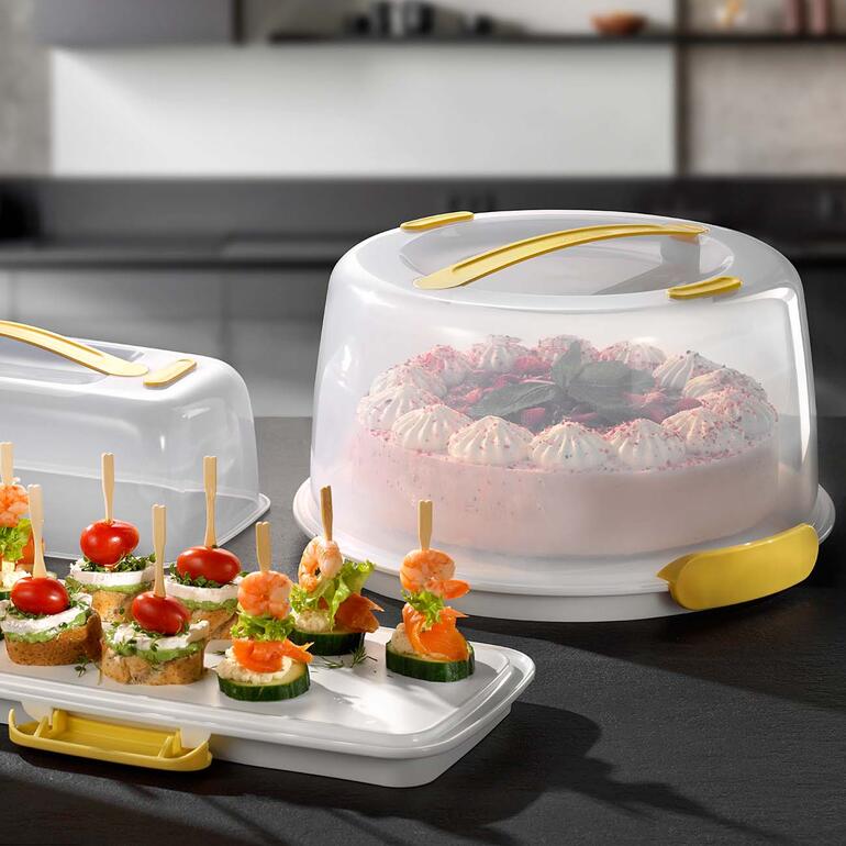 Koelende taartbutler met taart en snacks op een tafel.