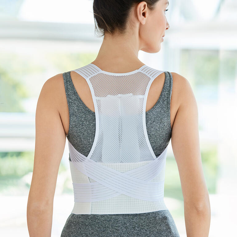 Vrouw draagt een universele houdingstrainer en toont de achterkant.