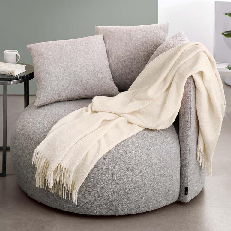 Alpaca bouclé deken op een zachte stoel.