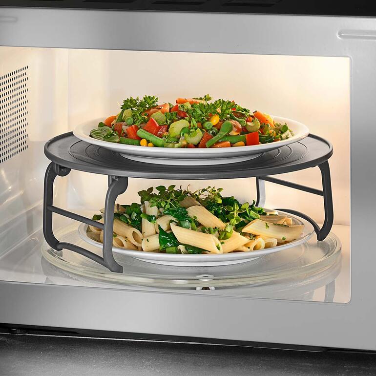 Magnetron etagère in een magnetron met groenten en pasta.