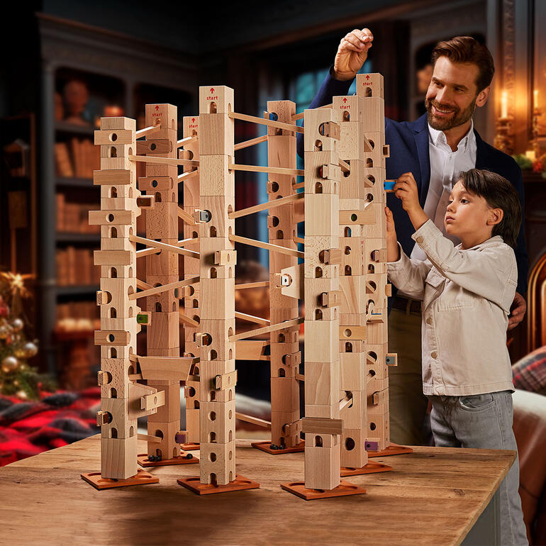 Xyloba-kogelbaan met houten blokken op een tafel, kinderen en volwassenen bouwen samen.