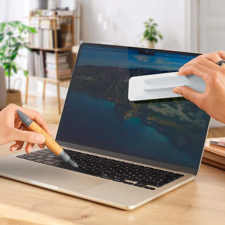 Handen gebruiken een 3-in-1 mobiele apparaat reiniger op een laptop