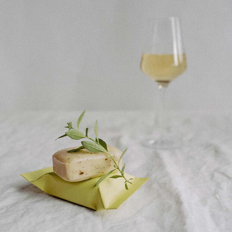 The Real Wine Soap® gesneden met bladeren, op de achtergrond een wijnglas.