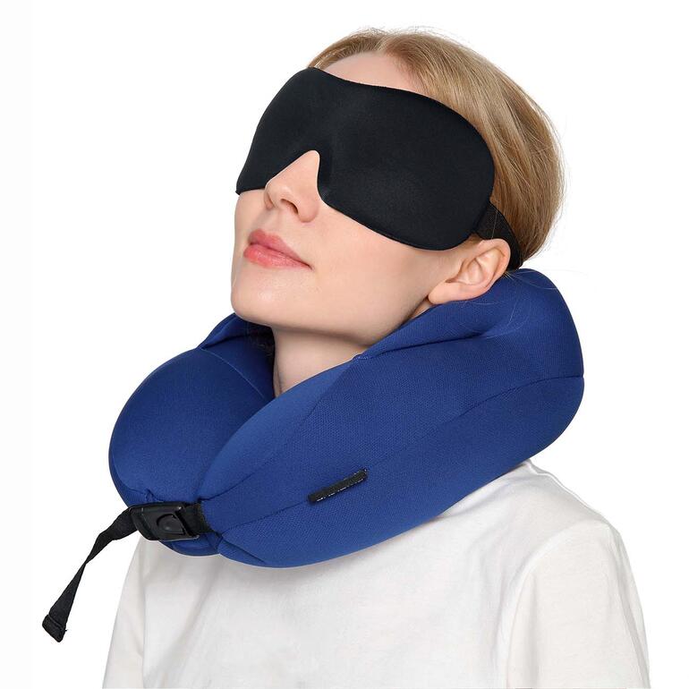 Vrouw draagt 3D contour slaapmasker en neksteun in het vliegtuig