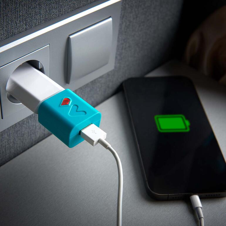Accubespaarder in het stopcontact terwijl een smartphone wordt opgeladen.