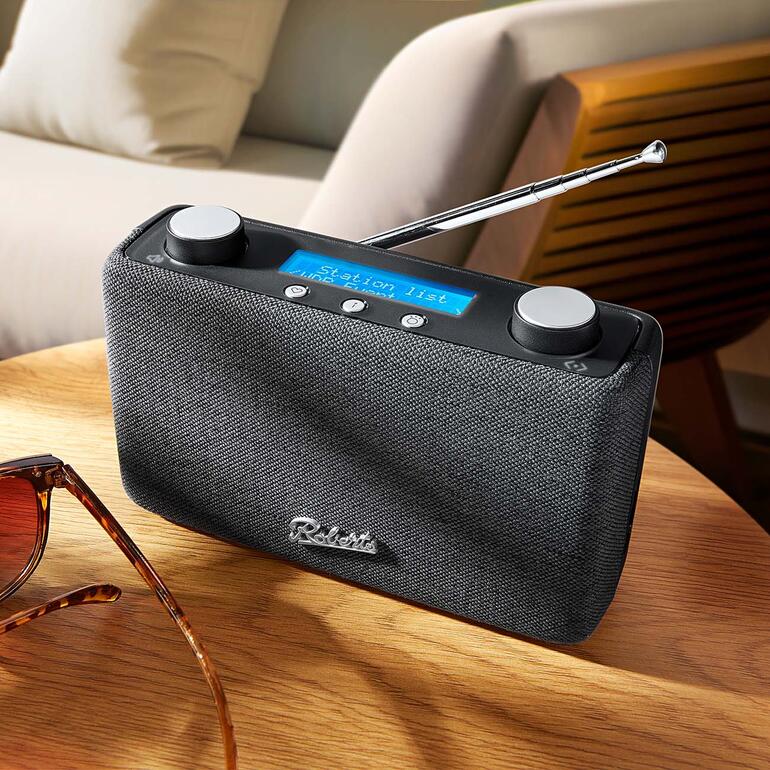 Roberts DAB+ Radio Play 11 op een tafel met zonnebril.