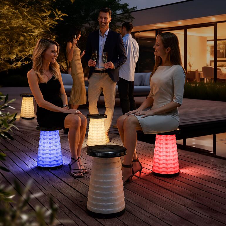 Twee vrouwen zitten op LED-telescoopkrukken op een tuinfeest.