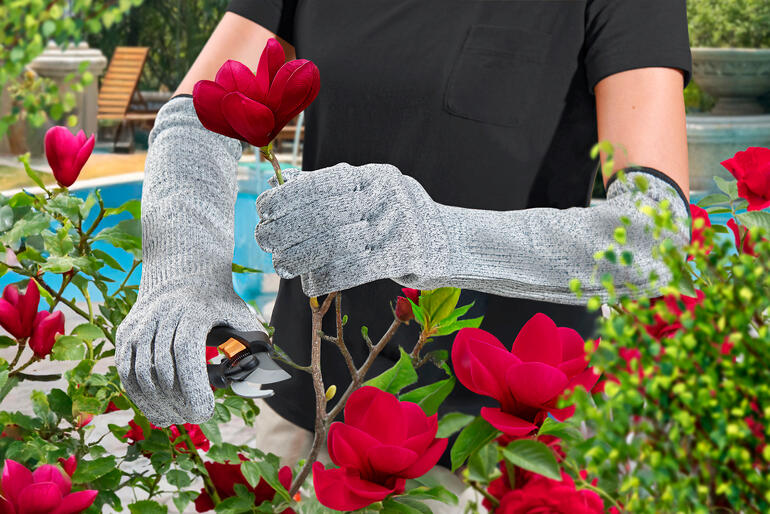 Tuinierster met safety-tuinhandschoenen snijdt een bloem.