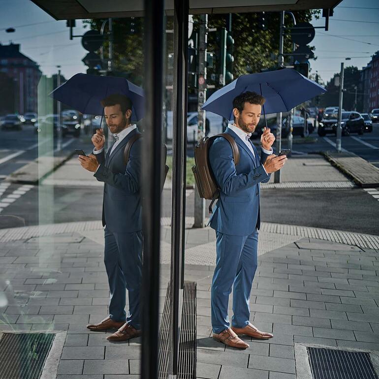 Man in pak met ultralichte paraplu op straat