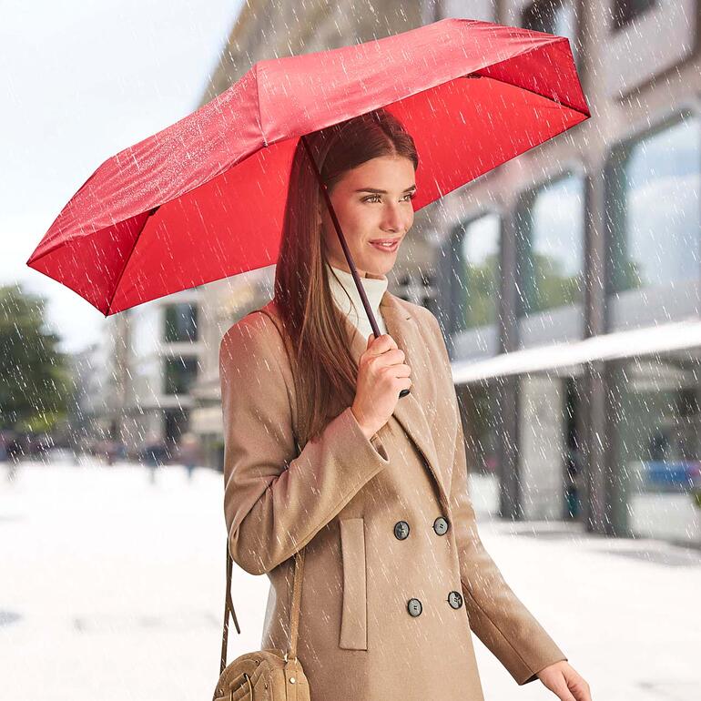 Vrouw met rode ultralichte paraplu in de regen
