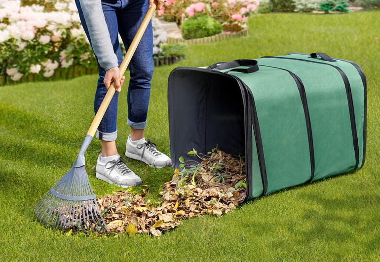 Persoon die bladeren in een vierkante tuinafvalverzamelaar op het gras veegt