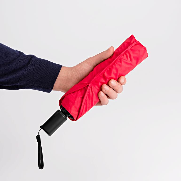 Hand houdt een opgevouwen rode tas paraplu vast