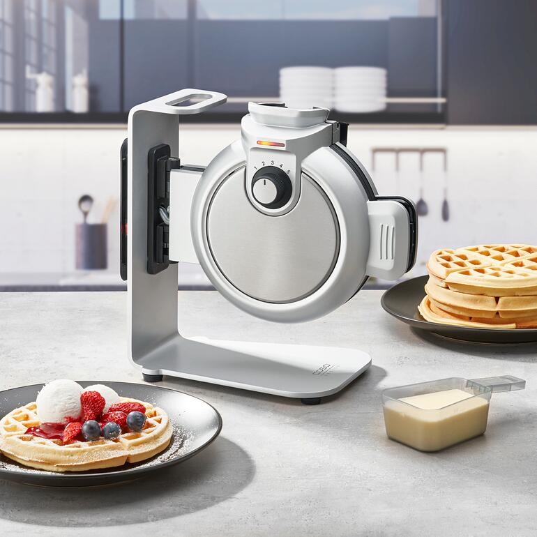 Verticaal wafelijzer Waffle Up met wafels en verse slagroom op de tafel.