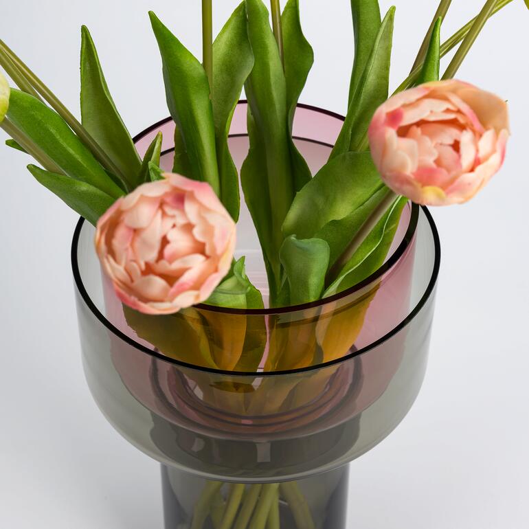 Vario-glazen vaas met tulpen en groen loof, in het midden van het beeld.