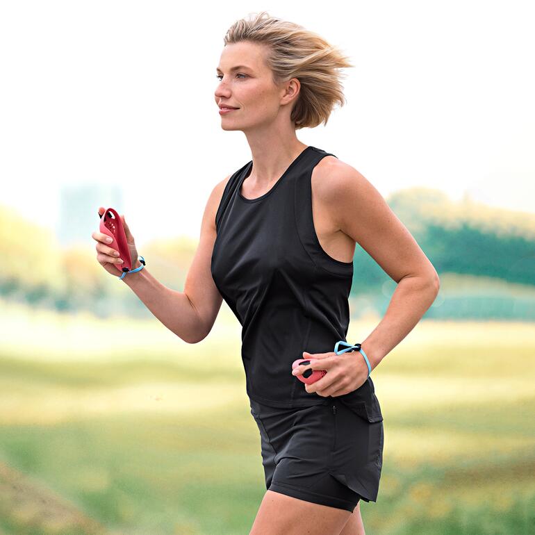 Vrouw jogt buiten, draagt sportkleding en houdt een loopmuis in de hand.