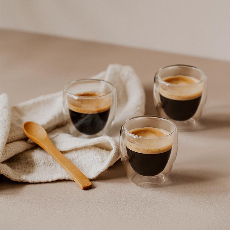 Espresso (80 ml, 6,5 cm h) Drie elegante espressothermoglazen met verse espresso op een tafel.