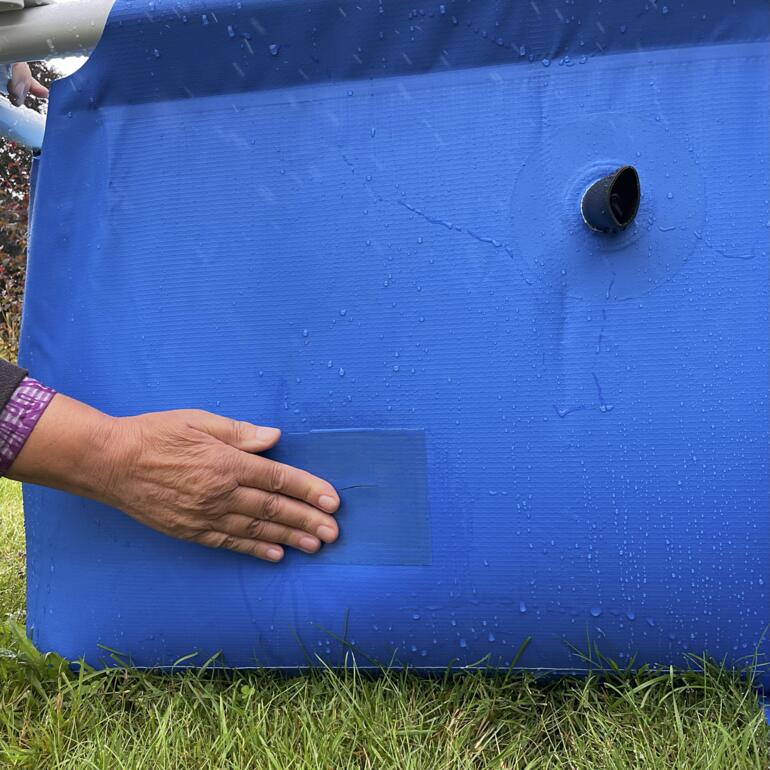 Persoon plakt onderwater tape op blauw poolmateriaal.