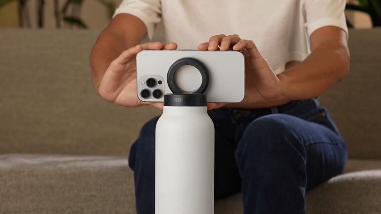 Persoon houdt een 2-in-1 drinkfles vast terwijl er een smartphone op balanceert.