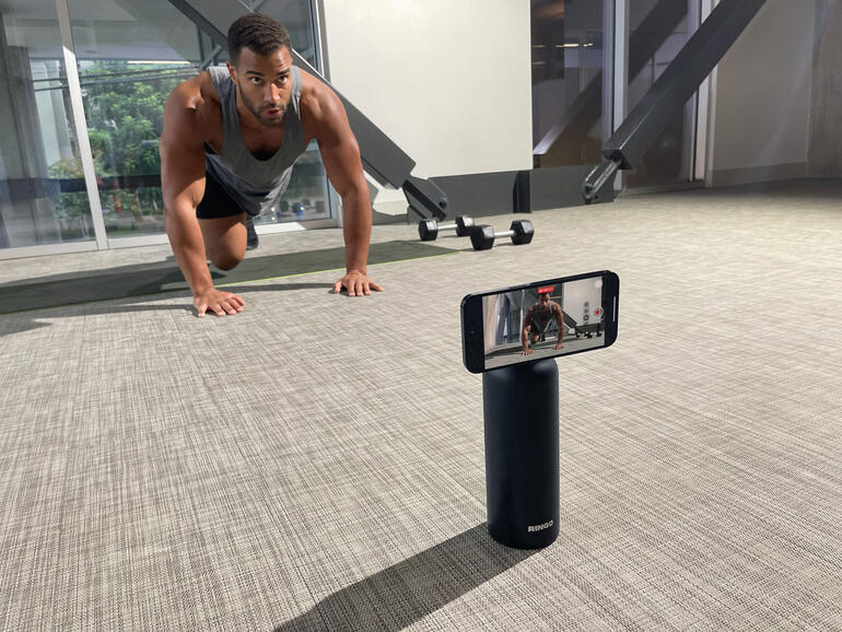 Man doet push-ups met de 2-in-1 drinkfles als houder voor zijn telefoon.