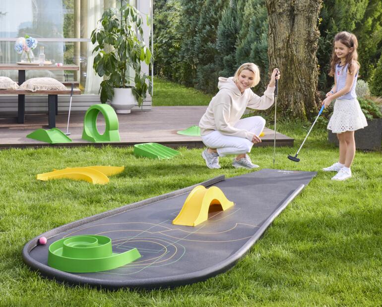 Vrouw met kind speelt minigolf op een draagbare minigolfbaan.