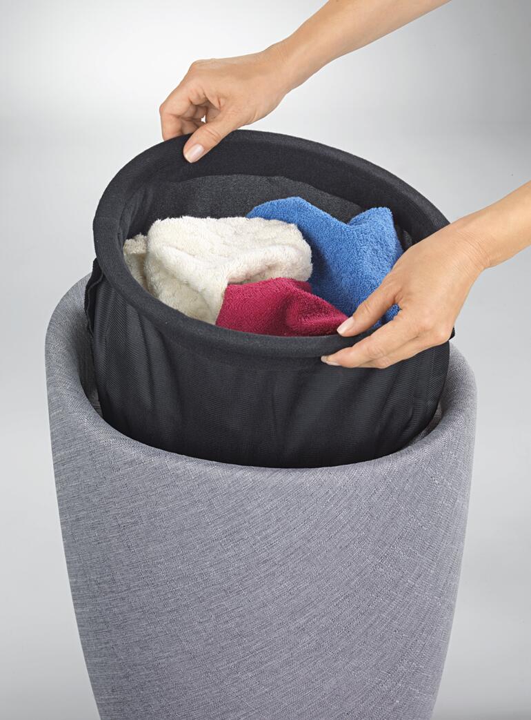 Waszak met zijdelingse handgrepen – voor het eenvoudig verwijderen. Handen die gekleurde handdoeken uit de wasmand halen.